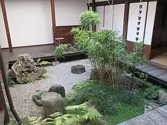 A square garden courtyard, about 2m on each side, with an engawa of broad dark boards about 30 centimetres (12&nbsp;in) above the pale gravel.