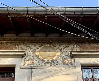 Renaissance Revival fresco with cartouches and foliage spirals on the upper part of the facade of Strada Occidentului no. 11, Bucharest, painter: C. Cora, architect: Cesare Fantoli, 1910[22]