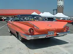 Rear view of a coral colored 1961 Buick with the license plate AINT PNK.