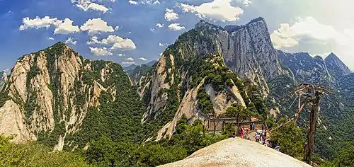 Mountain peaks partially covered by trees and some tourists