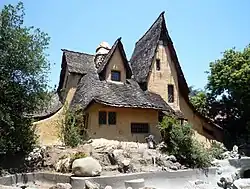 The storybook house with most landscaping removed, showing bare ground around the structure