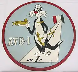 A This insignia was adopted in 1960. It features Sylvester the Cat wearing devices representing the three categories of naval personnel which make up the crew of an AVB: aviation, line, and Seabees. This ship's mission is represented by the runway, which emanates from two doors, symbolizing the bow doors of the ship. The colors on the doors are those of Italy where Alameda County is home ported. The runway markings represent the year (1957) in which this ship was designed AVB-1. Permission to use this copyrighted character was granted by Warner Brothers.