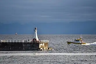 Pilot boat rounding lighthouse at Victoria, Canada and heading out to guide in a ship