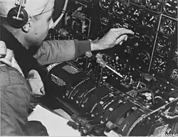 A black and white photograph of a man working at his control panel in a plane