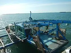 Blue wooden boat with outriggers and fishing equipment at the dock