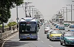 A blue trolleybus and other vehicles on a bridge.