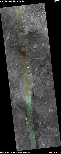 Wide view of mud volcano, as seen by HiRISE. The light-toned spots are the mud volcanoes. They have a different tone than the surroundings because they contain material brought up from depth. These structures may be useful to explore for remains of past life since they contain samples that would have been protected from the strong radiation at the surface. The colored strip is about 1&nbsp;km wide.