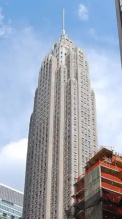 The exterior of 70 Pine Street, a stone-clad skyscraper, on a sunny day.