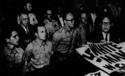 Black and white photo of several men standing at a court trial