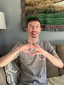 A man with Williams syndrome making heart hands.
