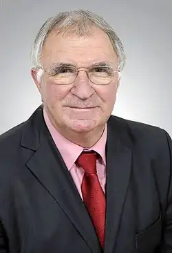 A bespectacled, middle-aged man in a suit and tie