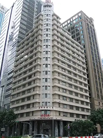 Beige rectangular building, 20 storeys and at 87 metres tall, with newer taller skyscrapers seen in the background.