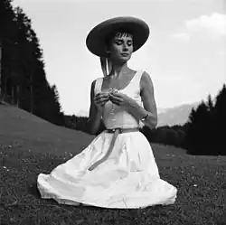 Hepburn in a light belted a-line sundress and straw hat in Switzerland, c. 1954
