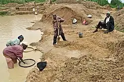 Three Sierra Leoneans in an open cast mine sieving for diamonds
