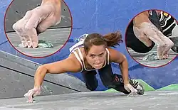 A climber using the crimping and edging technique on an indoor climbing wall