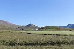Expansive fields with a farm in the distance and a mountain looming behind the farm