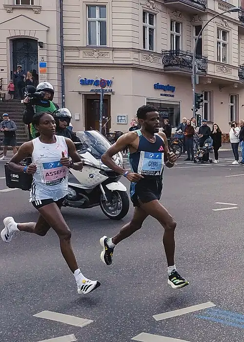 World record winner Tigst Assefa (left) about 25&nbsp;km (16&nbsp;mi) into the 2023 Berlin Marathon, alongside pacemaker Girmay Birhanu Gebru