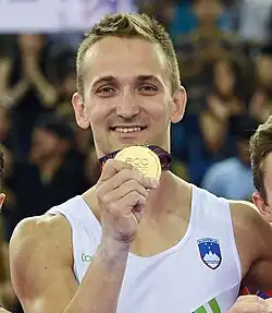 Portrait of Bertoncelj holding up a gold medal during the 2015 European Games.