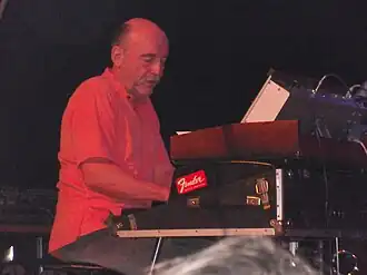 Martin Kratochvíl sitting behind keyboards, wearing a red short-sleeved shirt