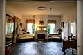 Photograph of the interior of the Bronson–Mulholland House standing in the rear parlor and looking into the front parlor.