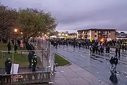Protesters on the street outside the Brooklyn Center police department as law enforcement stand on the other side of a fence