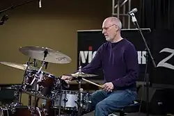 Man playing a drumset at a clinic session.