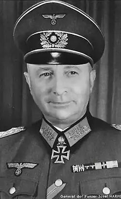 The head of an elderly man, shown from the front. He wears a peaked cap and a military uniform. His facial expression is a determined and confident smile; his eyes looks to the right of the camera.