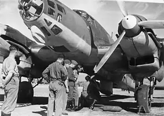 A large plane on the ground, with men looking underneath