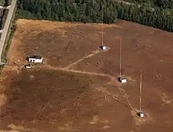 A set of three red-and-white towers on a bare plot of land