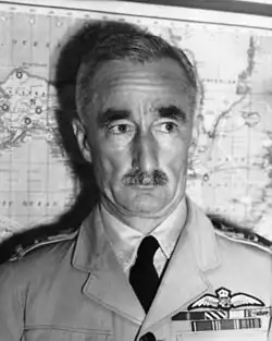 Head-and-shoulders portrait of moustachioed man in light-coloured military uniform with ribbons and pilot's wings on chest