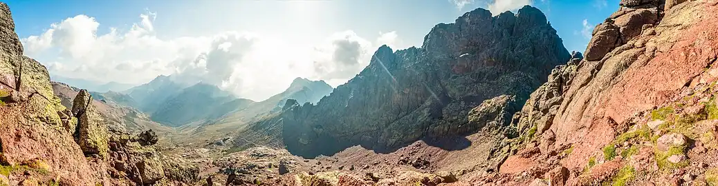 Panoramic photo of Capu Tafunatu (east face, in the shade) and the Col des Maures (Moorish Pass), above the Ciottulu a i Mori refuge in the upper Golo Valley. One can distinguish in the wall the turns of the normal access route leading to the "hole".