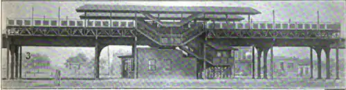 A side view of a train station with its surroundings cleared, showing the station house, stairwells, and platforms