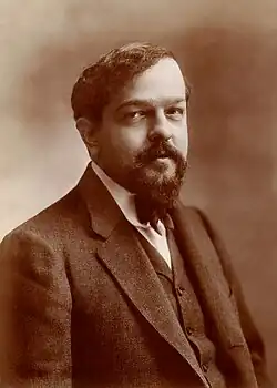 middle-aged white man with full head of dark hair and neat moustache and beard