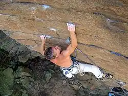 A climber using the crimping and edging technique on an outdoor rock face
