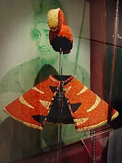 Hawaiian royalty wore these feathered cloaks (ʻahu ʻula) and helmets. The chief in the background is Kaʻiana.