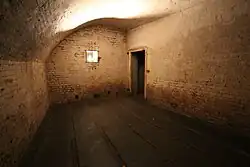 View of a cartridge magazine in the fort, an empty room with an arched ceiling and grooved wooden battens covering the floor