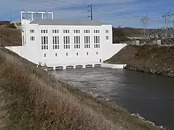 Hydropower plant with tailrace canal running out of base; transformer substation on bank