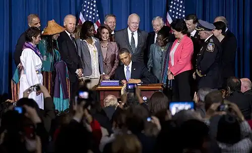 Photograph of Barack Obama signing the VAWA reauthorization, surrounded by numerous major players, including Deborah Parker