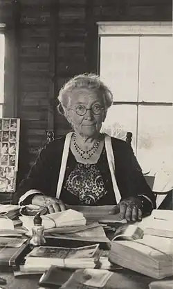 Photograph of Cornelia Clapp sitting at a desk covered with bound stacks of papers