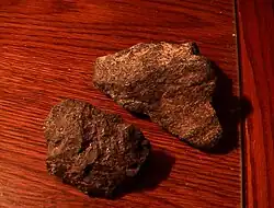 Two rough chunks of cumberlandite showing reddish brown coloring with a few whitish streaks.