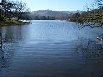 A lake surrounded by trees with mountains beyond