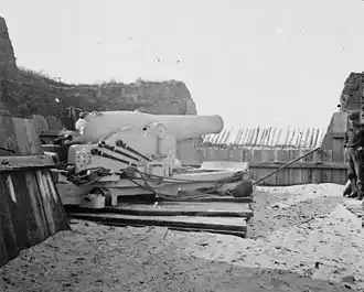 A nine-inch (229&nbsp;mm) Union navy Dahlgren gun set up on land for siege work as they were at battery ten at Port Hudson. The gun is whitewashed so it can be more easily worked at night. The projections at the breech are for the navy double vent percussion firing system. The crewman at the far right is wearing the Union navy uniform.