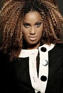 Daisy Dee wearing a black and white top, looking directly at camera