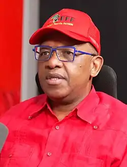 A man wearing blue frame glasses, a red baseball cap and a red button-up shirt