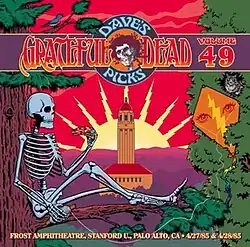 A skeleton sitting on the branch of a tree and eating a slice of pizza, with Hoover Tower in the background