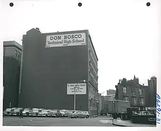 Large, windowless wall with cars parked