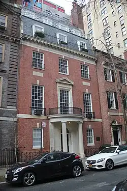 A brick townhouse with slate roof and semicircular entrance portico