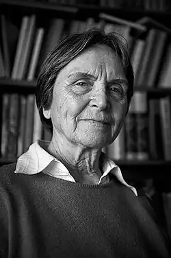 Photography of Erika Taube, an older woman with short hair, wearing a collared shirt and sweater.
