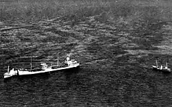 An oil tanker is towed by a small tugboat