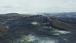Cooled lava fields can be seen, whilst the Fagradalsfjall volcano erupts in the background